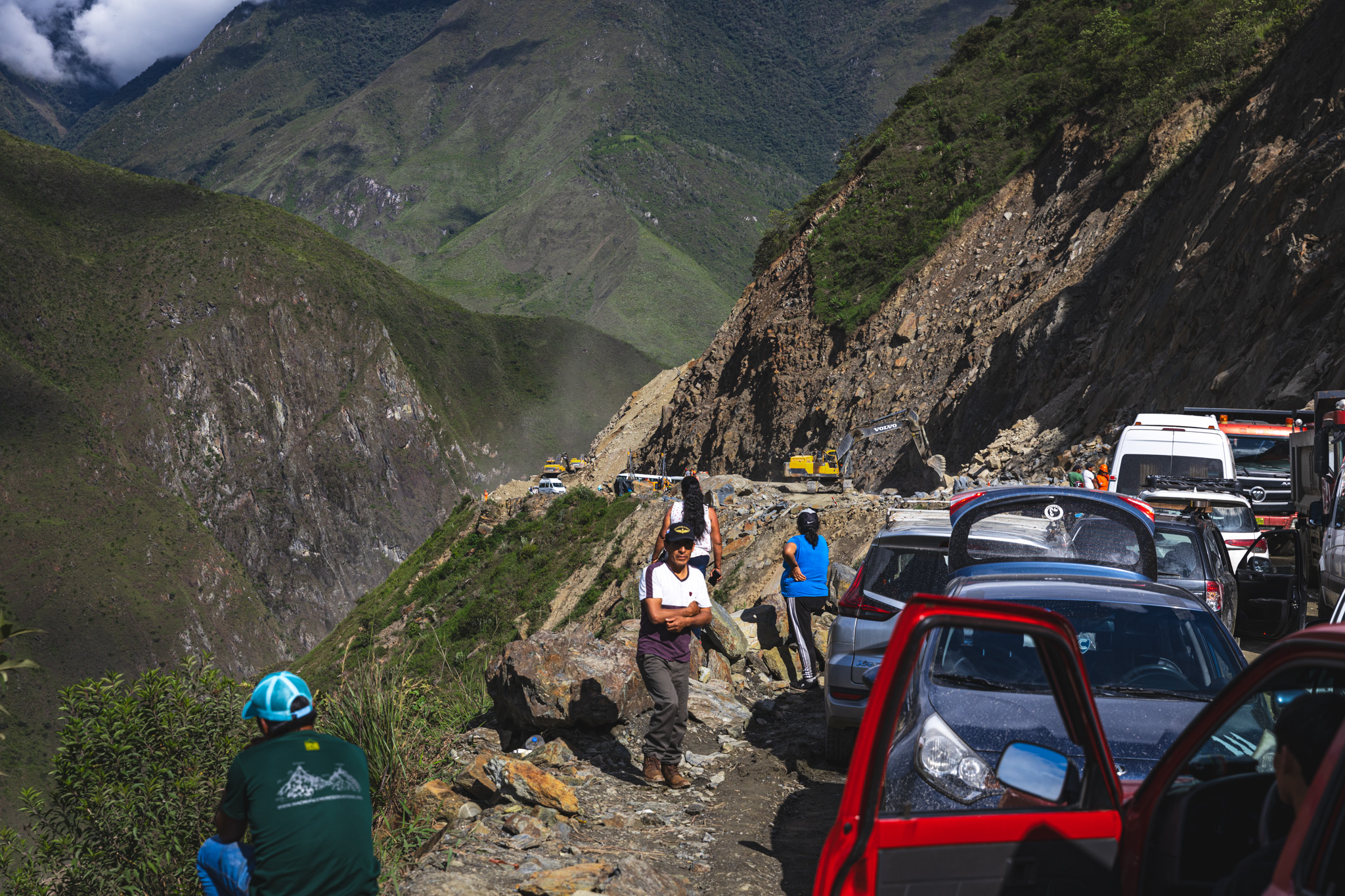 Cars stopped on a cliff edge, waiting for debris on the road to be cleared