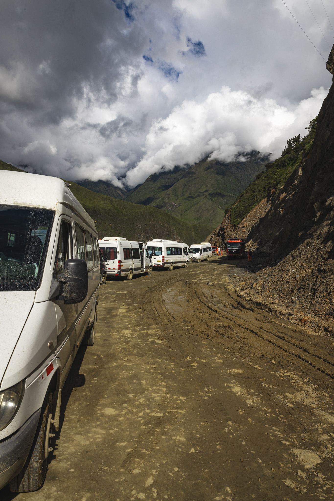 Commuter vans on a cliff edge, waiting for debris on the road to be cleared