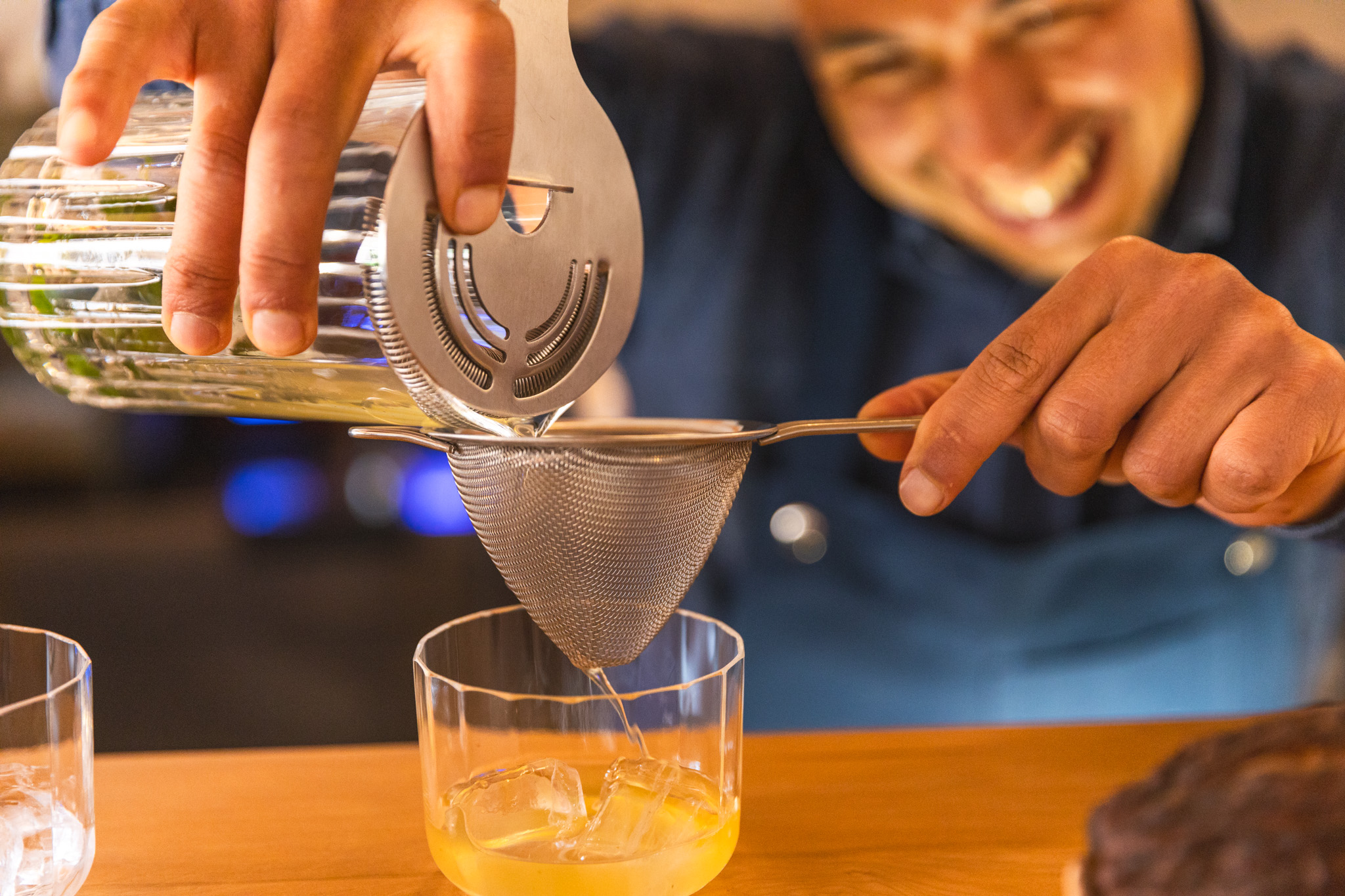 Straining cocktail mixture into a glass